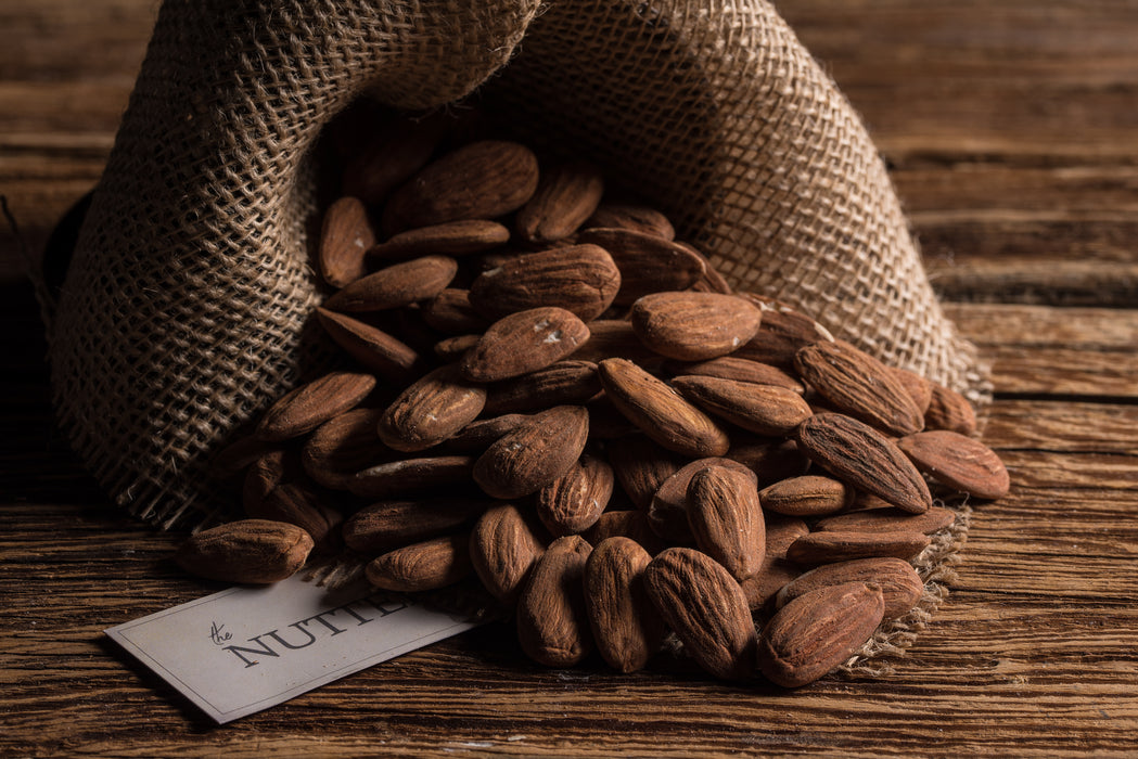 Whole roasted almonds with a light salt coating, packaged elegantly in a burlap-style bag.