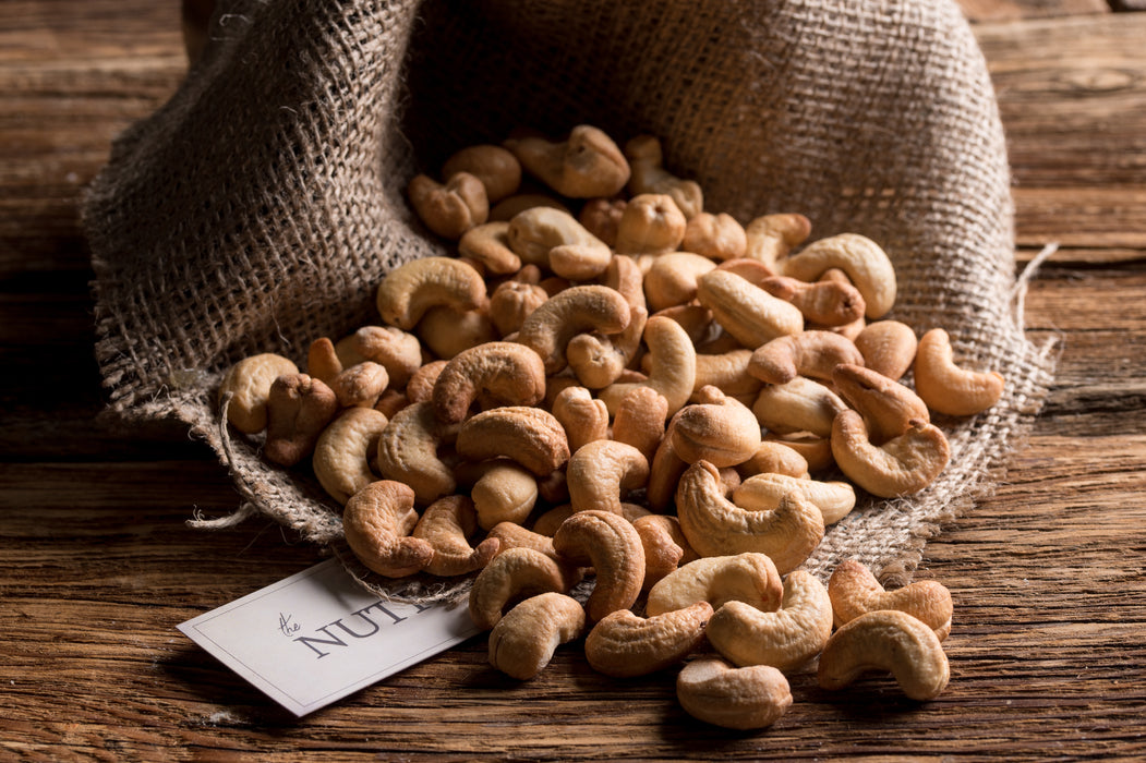 Golden roasted cashews lightly salted and presented in a rustic burlap-style sack.