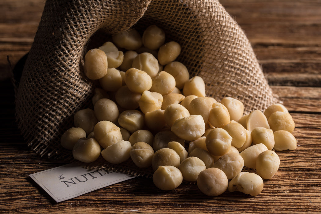 Whole roasted macadamia nuts lightly salted and packaged in a burlap-style sack.