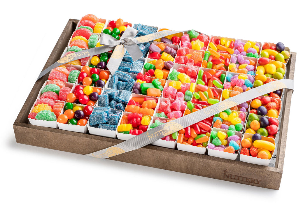 Large gift tray with individual party cups filled with assorted candies, including gummies, sour belts, and jelly beans, wrapped with a signature ribbon.