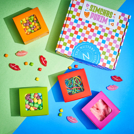 A cheerful candy gift set featuring four colorful boxes of gummies, including rainbow sour belts and fruit chews, arranged beside a checkered "Simchas Purim" gift box. The bright colors and themed packaging make this a fun and festive treat for the holiday.