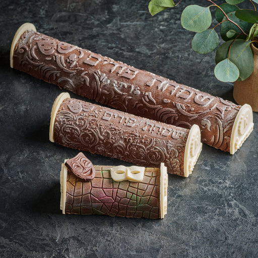 An exquisite trio of Chocolate Purim Logs, each designed with unique holiday-themed patterns. This set includes a large embossed log, a smaller version with a similar design, and a mini log decorated with a theatrical mask and festive colors—perfect for celebrating Purim in grand style.