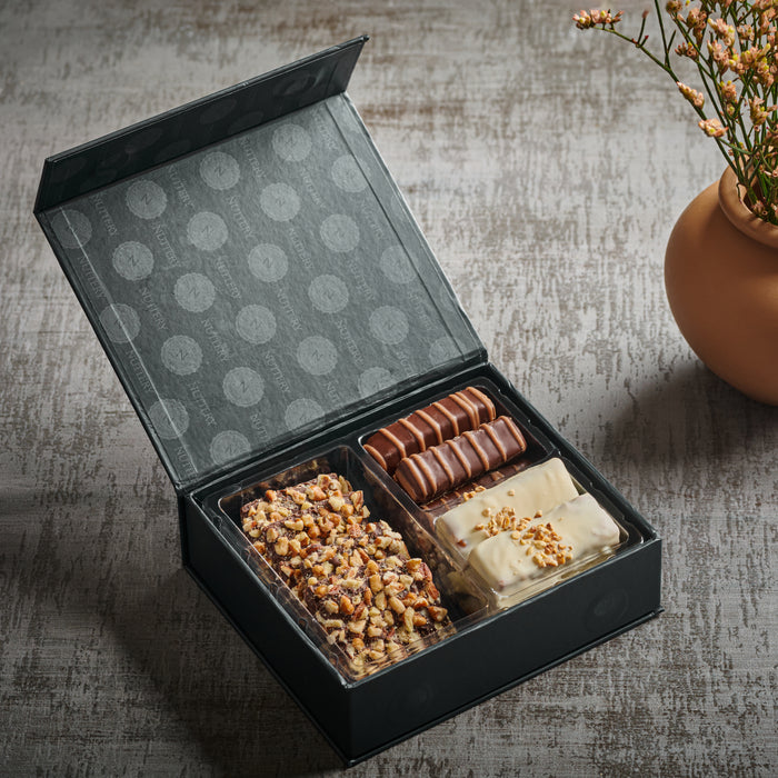 A beautifully curated collection of handcrafted chocolate bars, nut clusters, and rich confections. Packaged in a sophisticated black box, this gourmet gift is a perfect balance of taste and elegance.