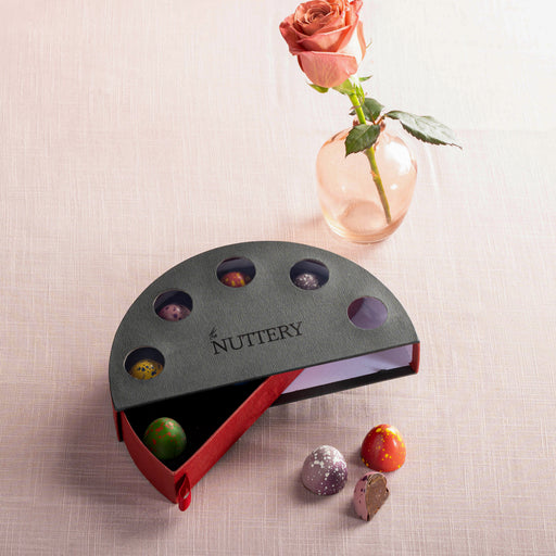 A luxurious chocolate gift box featuring a sleek black and red design with a semi-circular shape, showcasing gourmet artisanal chocolates in an elegant presentation.