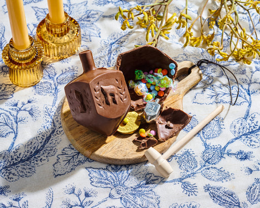 The Nuttery NY chocolate smash dreidel, shown cracked open to reveal colorful candies, chocolate coins, and festive surprises, making it a delightful Hanukkah celebration gift.