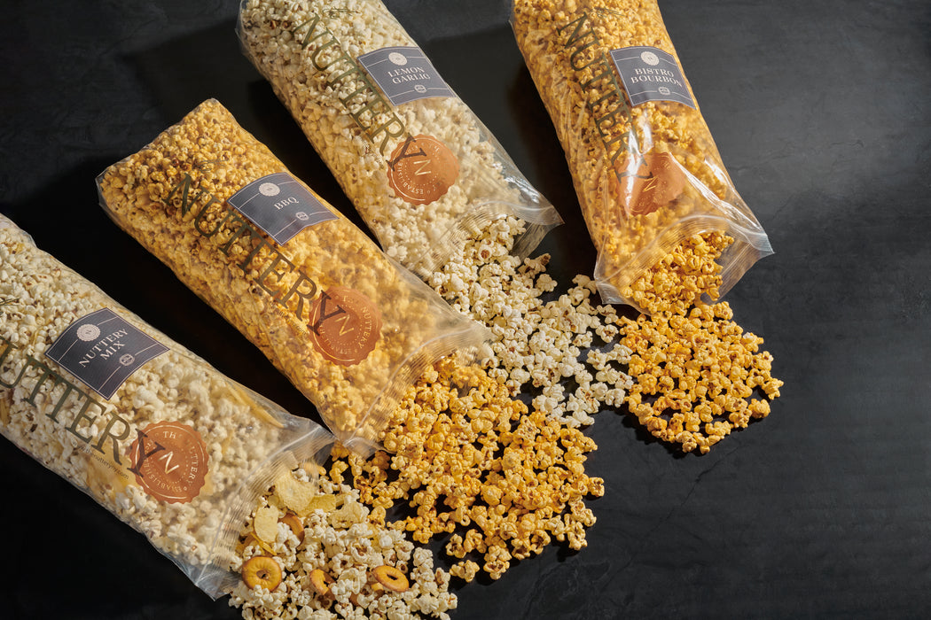 Close-up view of four bags of premium popcorn in various flavors, showcasing their rich textures and colors, ideal for snacking or gifting.