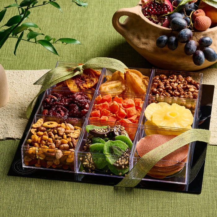 A premium acrylic gift tray featuring an extravagant display of dried fruits, including pineapple, apricots, figs, and candied citrus, elegantly tied with a gold ribbon.