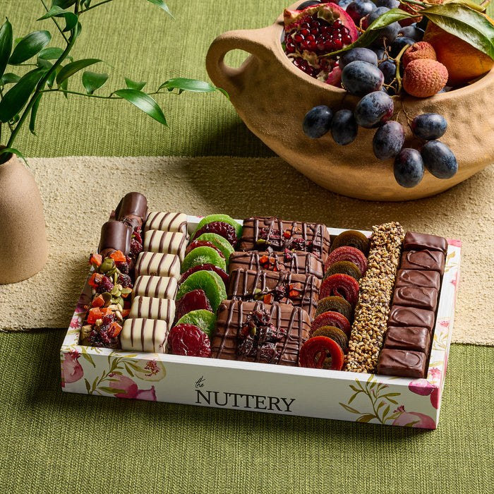 An elegant Tu B’Shvat gift tray from The Nuttery, featuring an assortment of dried fruits, nuts, and chocolates, beautifully arranged in a pomegranate-themed collection.
