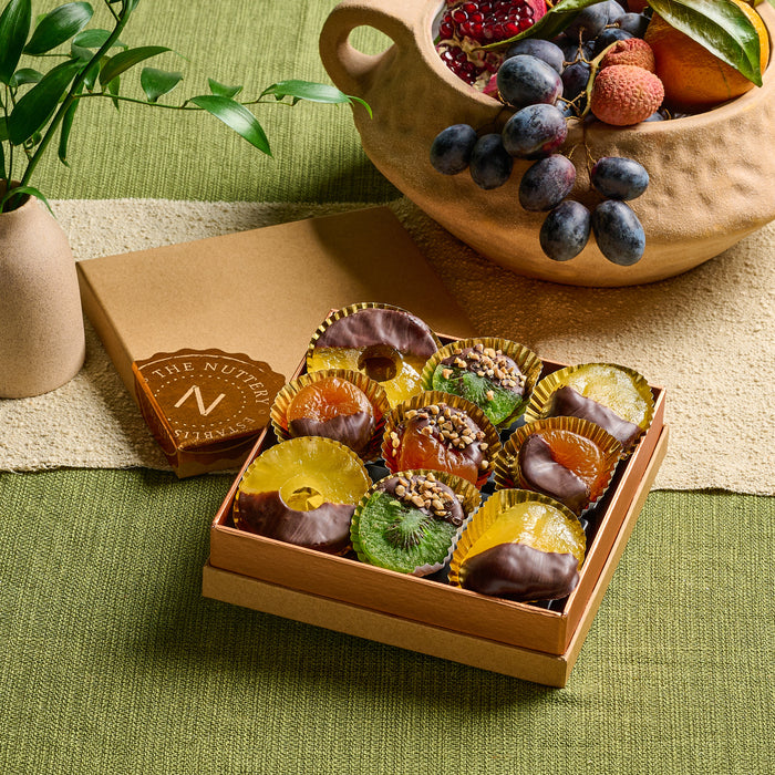 A beautifully arranged gift box featuring an assortment of dried fruits dipped in rich chocolate and topped with seeds and nuts, perfect for Tu B’Shvat.