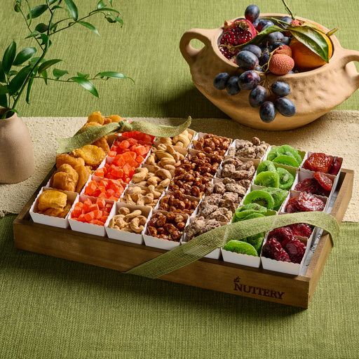 An elegant wooden tray filled with a colorful assortment of dried fruit and nuts, tied with a green ribbon, perfect for Tu B’Shvat celebrations.