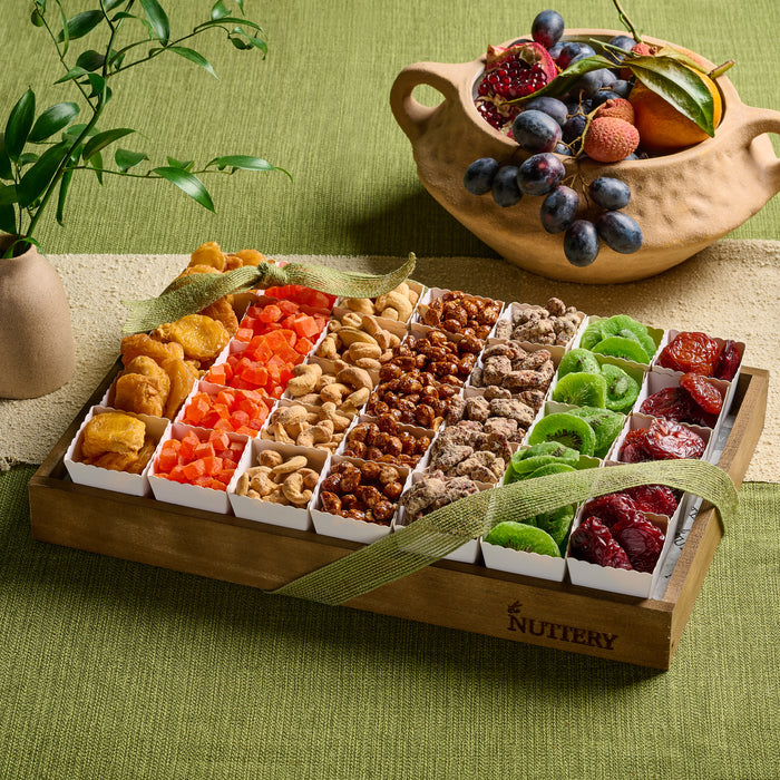 An elegant wooden tray filled with a colorful assortment of dried fruit and nuts, tied with a green ribbon, perfect for Tu B’Shvat celebrations.