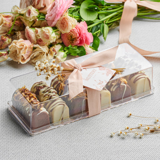 A luxurious set of six mini cheese logs, coated in smooth milk and white chocolate, topped with a drizzle of caramelized nuts for a perfect balance of crunch and sweetness.