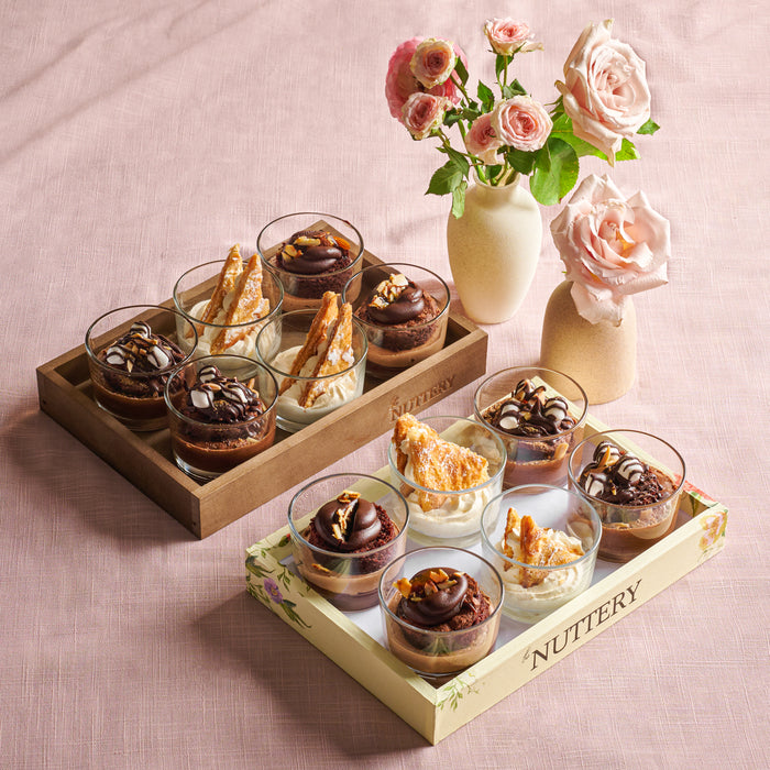 A set of gourmet mousse cups arranged in a floral-themed Nuttery gift tray, featuring layers of chocolate and cream with elegant toppings.