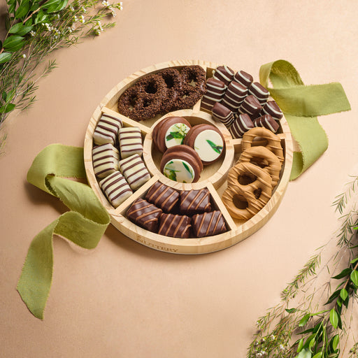 A beautifully arranged round platter of assorted chocolates and treats, tied with a green ribbon, perfect for Sukkot celebrations or gifting