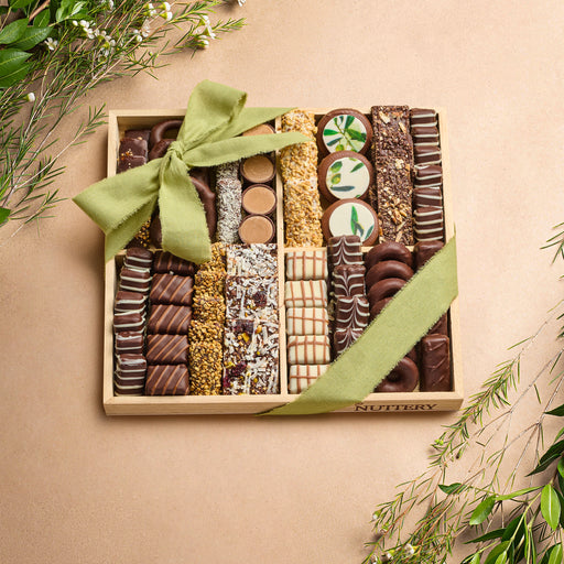 A beautifully arranged wooden gift tray filled with an assortment of gourmet chocolates, wrapped with a green bow, perfect for gifting.