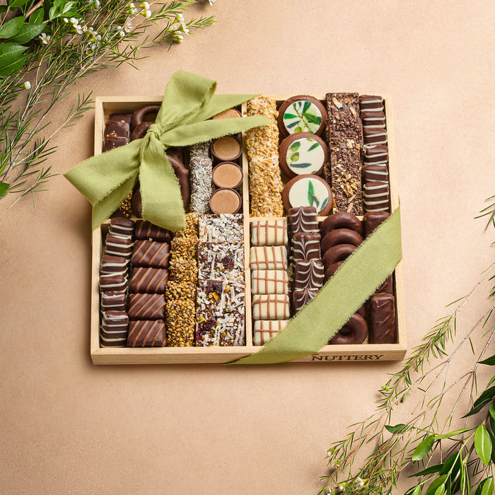 A beautifully arranged wooden gift tray filled with an assortment of gourmet chocolates, wrapped with a green bow, perfect for gifting.