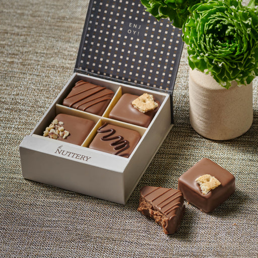 Mini truffle gift box featuring four gourmet dairy chocolates with unique toppings, presented in an elegant gray box with a polka-dot interior design, perfect for gifting.