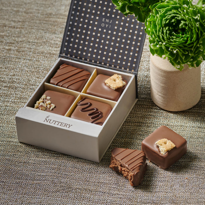 Mini truffle gift box featuring four gourmet dairy chocolates with unique toppings, presented in an elegant gray box with a polka-dot interior design, perfect for gifting.