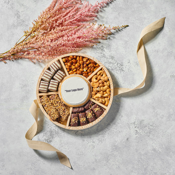 The Nuttery NY custom corporate gift trays, featuring an elegant selection of premium chocolates, roasted nuts, and gourmet confections, personalized with a custom logo on a chocolate plaque.