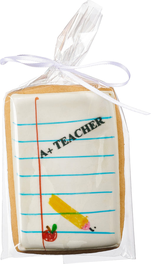 A decorated sugar cookie shaped like a notepad, featuring an "A+ Teacher" message with a pencil and apple design, individually wrapped for a thoughtful teacher appreciation gift.