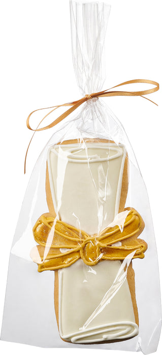 A decorated sugar cookie shaped like a diploma, wrapped in a clear gift bag with a gold ribbon, perfect for celebrating graduates.