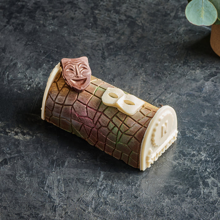 A delightful single-serving chocolate log, this miniature Purim treat features a multicolored chocolate shell adorned with a comedy mask and masquerade glasses—symbolizing the joyous spirit of Purim. The meticulously crafted details make it a whimsical yet sophisticated holiday gift.
