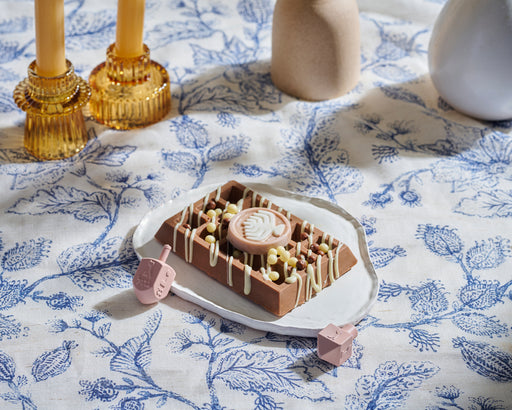 Chanukah chocolate waffle elegantly plated on a floral tablecloth, surrounded by candles and festive decorations for a holiday celebration.