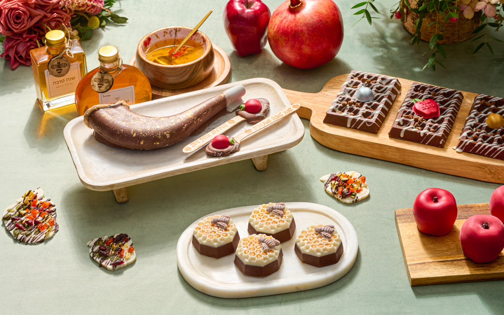 The Nuttery Chocolate Honeycombs – a luxurious selection of honey-infused chocolates, artfully arranged with pomegranates, fresh flowers, and a honey dipping bowl for a festive presentation.