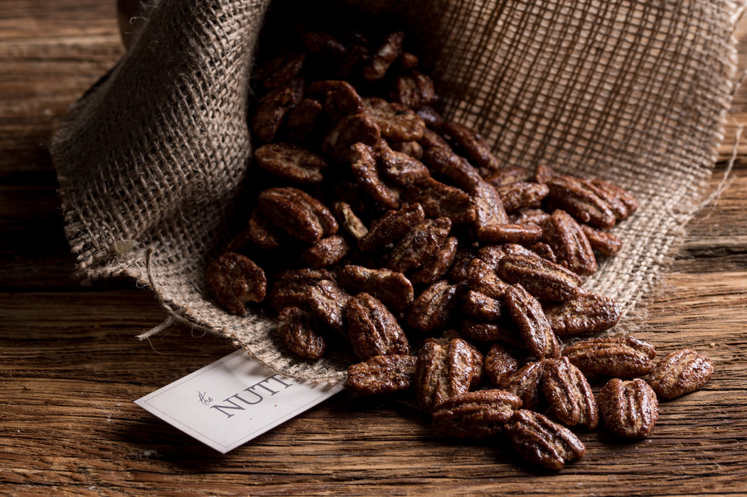 Caramelized sweet pecans with a glossy finish, packaged in a rustic burlap-style sack for Passover gifting.