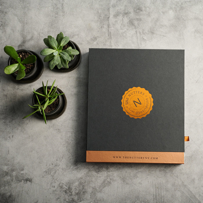 A top-down view of the open gift box, highlighting a carefully curated selection of roasted nuts, chocolate-dipped treats, and crunchy delights.