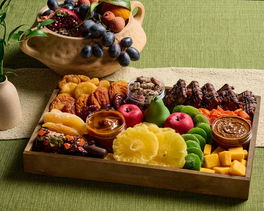 A gourmet fondue tray from The Nuttery, featuring a variety of fresh and dried fruits, chocolates, and nuts, designed for a sweet and interactive dessert experience.