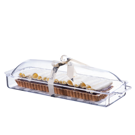 Rectangular tart topped with caramelized almond brittle, presented in a clear acrylic serving tray and tied with a branded cream ribbon, perfect for gifting or dessert tables.