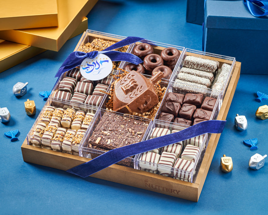 The Ultimate Chanukah Chocolate Gift Tray is a luxurious assortment of rich chocolates and festive treats, perfect for celebrating the holiday. Featuring an elegant mix of chocolate-covered nuts, gourmet confections, and a signature chocolate dreidel, this beautifully packaged tray is a sophisticated gift for any occasion.