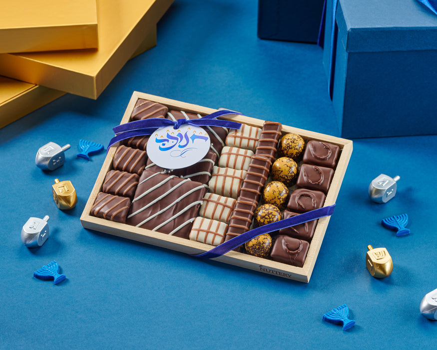 The Chanukah Small Chocolate Elegance Tray is a festive selection of gourmet chocolates, carefully arranged and tied with a decorative ribbon. This beautifully presented assortment makes a perfect holiday gift or indulgent treat for any celebration.