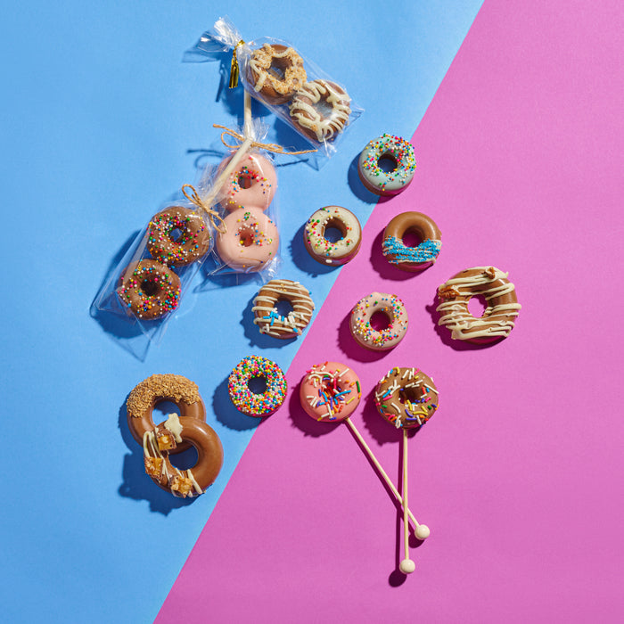 A playful assortment of donut-shaped chocolate pops, coated with colorful sprinkles and drizzles, designed for festive Hanukkah celebrations.