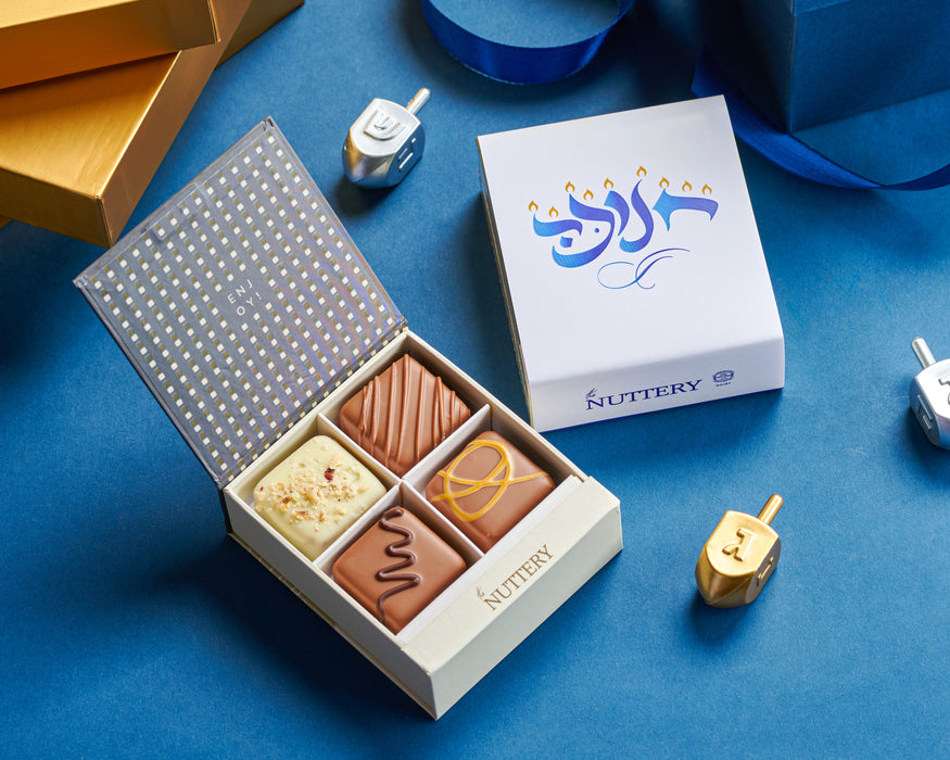 A festive Hanukkah-themed chocolate gift box featuring four gourmet truffles, presented alongside traditional dreidels for a perfect holiday treat.