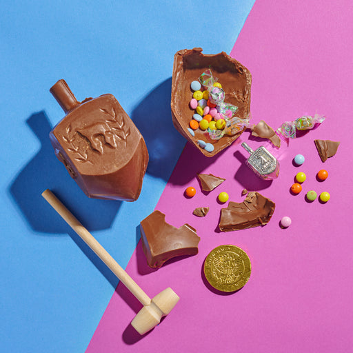 The Nuttery NY Hanukkah mini chocolate smash dreidel, crafted from rich milk chocolate and featuring traditional Hebrew engravings, presented with a wooden mallet for a fun and festive treat.
