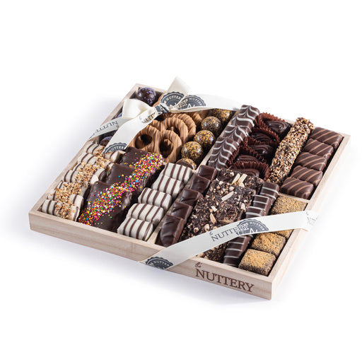 Large wooden gift tray filled with assorted specialty chocolates, cookies, and truffles, tied with branded Nuttery ribbons for an elegant presentation