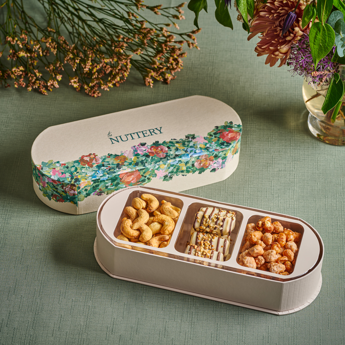 A beautifully designed floral gift box filled with an assortment of chocolate-covered nuts and caramelized treats. The elegant packaging makes it a perfect gourmet gift for special occasions, combining luxury snacking with artistic presentation.
