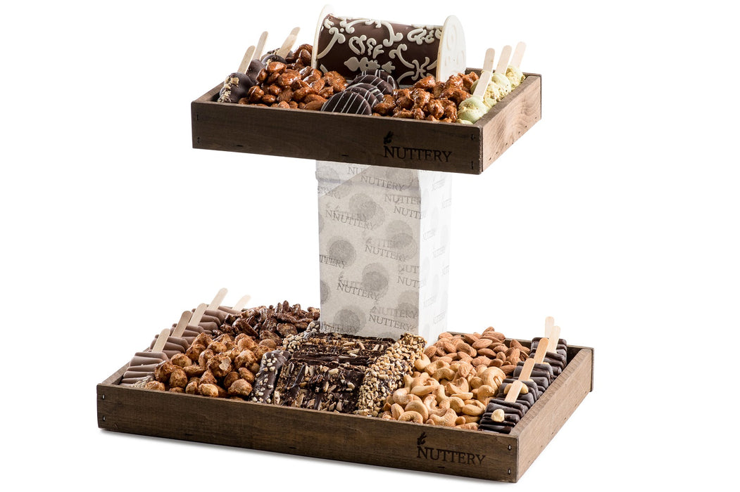 Two-tiered wooden gift tray featuring gourmet nuts, chocolates, and treats from The Nuttery, elegantly arranged for gifting.