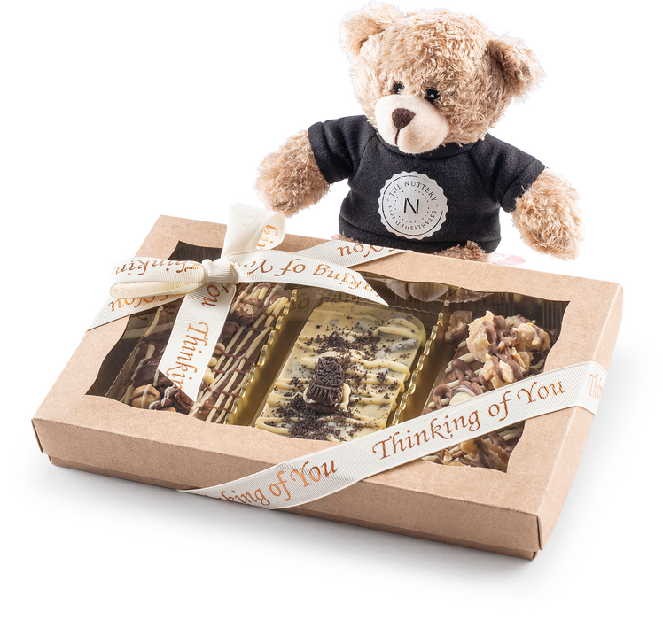A charming gift set featuring The Nuttery’s dairy chocolate tart box, paired with a soft teddy bear wearing a branded T-shirt, wrapped in a ribbon that reads "Thinking of You" for a sweet and thoughtful gift.