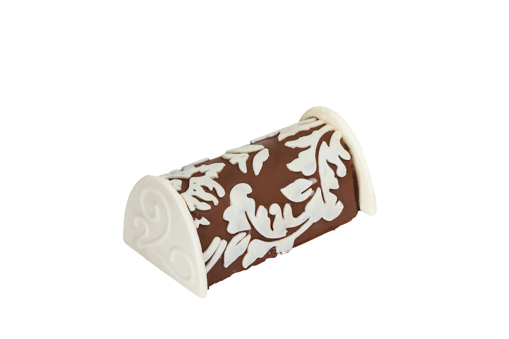 A decadent chocolate praline log with a beautiful handcrafted white chocolate overlay. This exquisite treat combines artful design with a rich and creamy filling.