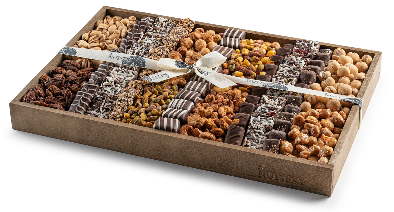 Large wooden tray featuring an assortment of premium nuts and chocolates, elegantly arranged in rows and tied with a branded white ribbon, ideal for sharing or gifting.