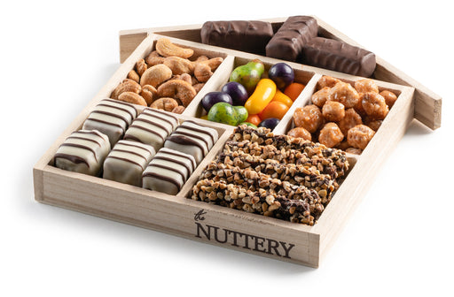 A wooden house-shaped gift tray filled with chocolate-covered treats, gourmet nuts, and colorful candy, offering a delightful mix of flavors and textures.