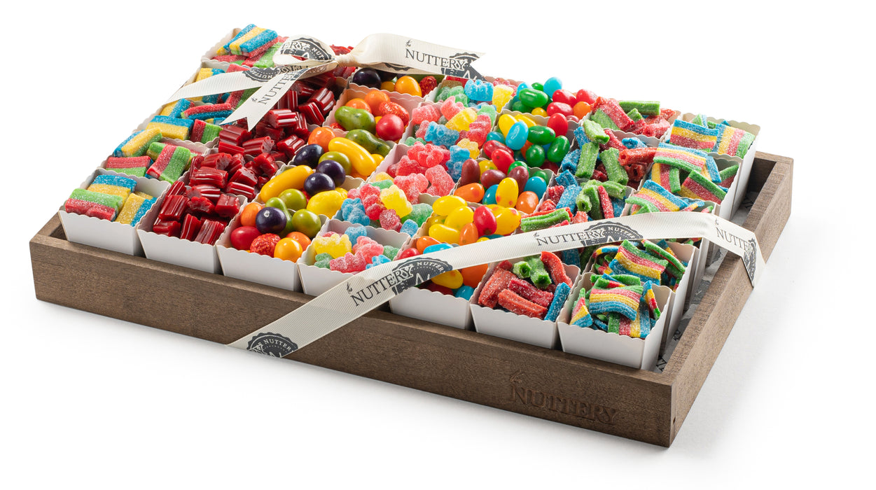 Assorted candy gift tray with individual party cups filled with colorful gummy candies, sour belts, jelly beans, and licorice, elegantly presented in a wooden tray from The Nuttery NY
