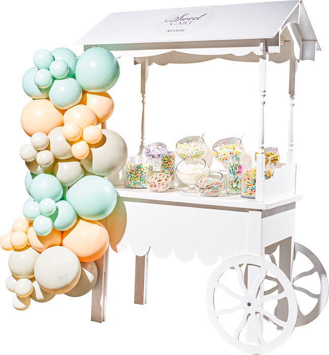 A pink-themed candy cart from The Nuttery, featuring a variety of pink and red sweets, making it a perfect centerpiece for weddings and parties.