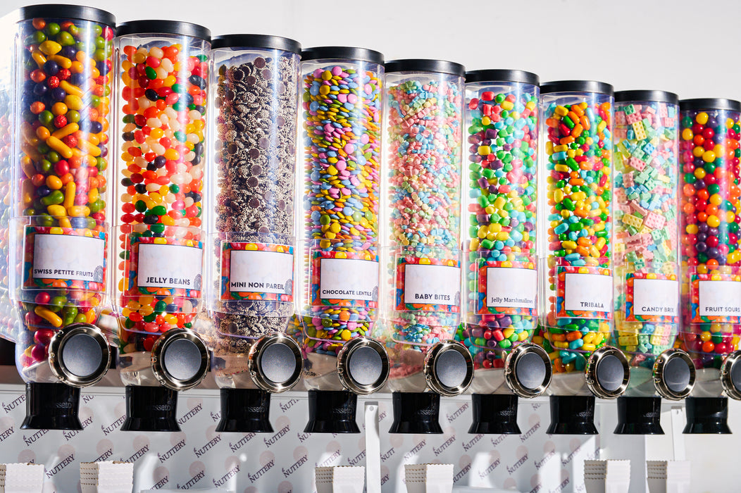 Close-up of candy dispensers filled with vibrant treats such as jelly beans, mini nonpareils, and marshmallows.